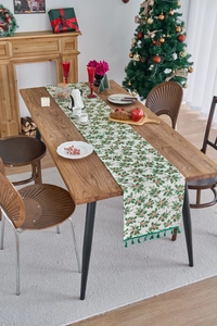 Detail of Christmas table runner with holly leaf prints and green tassel ornaments