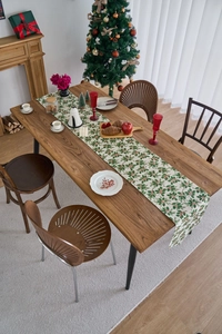 Detailed view of Christmas table runner with green holly leaves and red berry patterns