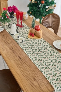 Dettaglio runner da tavola natalizio beige con aghi di pino e bacche rosse
