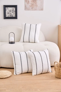 Detail view of modern white cushions with black geometric embroidery on a cozy sofa