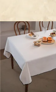 Detail showing white tablecloth fabric with black wavy embroidery and elegant drape