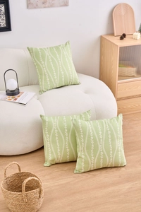 Detail of light green floral cushion covers with white leaf stripes on a modern sofa