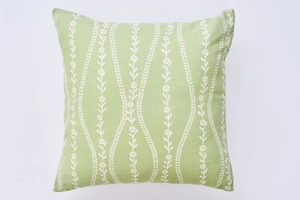 Detail shot of the durable fabric texture and white floral pattern on a green cushion cover