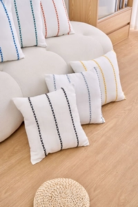 Detailed close-up of modern geometric embroidery on white textured cushion covers