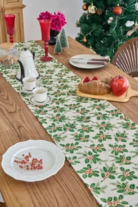 Detailed view of festive Christmas table runner with green leaf and red berry prints