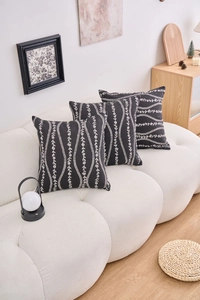Detail of three black and white floral embroidered square pillow covers in a modern setting