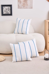 Detail of white cotton linen cushion covers featuring blue geometric embroidered stripes