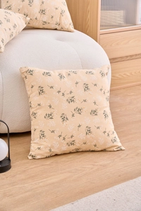 Close-up of beige cushion cover with floral pattern on a cozy Nordic home background