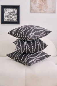 Detailed view of three stacked black and white floral patterned pillow covers on a sofa