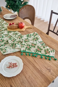 Detail of Christmas table runner with holly berries print and green fringe tassels