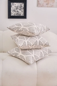 Detailed texture of three modern geometric patterned cushion covers on a beige fabric sofa