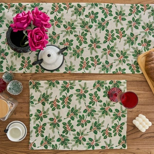 Detailed top view of Christmas table runner with green holly leaves and red berry patterns