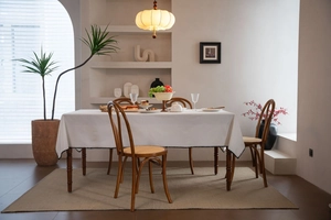 Close-up of white linen tablecloth featuring black wavy edge stitching on a wooden dining table