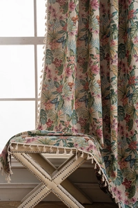 Detail of floral and bird jacquard curtain with tropical leaves and cream fringe tassels