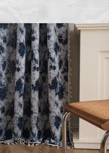 Close-up of blue floral jacquard curtain fabric with decorative cream tassel fringe edge