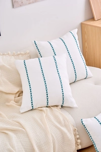 Detail of white cotton linen cushion cover featuring vertical teal embroidered stripes