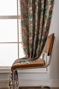 Detail of floral jacquard fabric showing pink flowers and cream cotton tassels on a chair