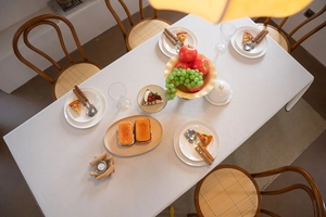Top view of a white textured tablecloth on a dining table with wooden rattan chairs