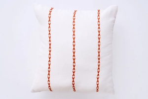 Detail of white square cushion cover with orange V-shape embroidered patterns