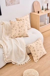 Set of three beige floral cushion covers on a white sofa in a cozy interior setting