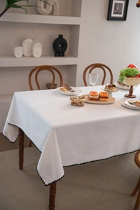 Close-up of white tablecloth with black wavy crochet lace edge on a wooden table