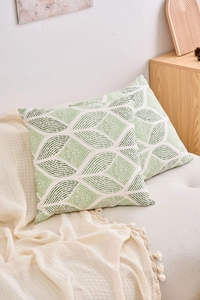 Detail of green geometric pattern cushion covers on a sofa in a modern minimalist setting