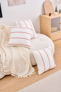 Detail view of cream cushion cover with orange geometric arrow embroidery and cotton texture