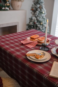 Close-up of red and green plaid thick wool tablecloth in a cozy Christmas dining setting
