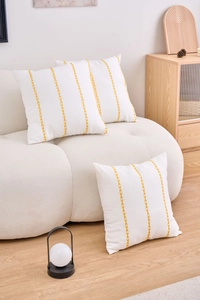 Detailed macro view of three square cushion covers with yellow embroidered arrow patterns