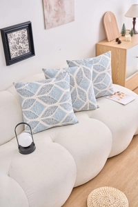 Close-up of blue geometric leaf pattern cushions on a modern white sofa setup