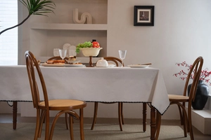 Detail of cream tablecloth featuring elegant black wavy scalloped edges on a dining table