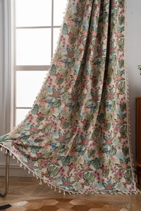 Close-up of floral and butterfly jacquard curtain fabric with white tassel trim details