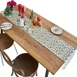 Christmas table runner with green holly leaves and red berries on a rustic wooden table