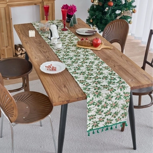 Christmas table runner with green holly leaves, red berries, and decorative tassels
