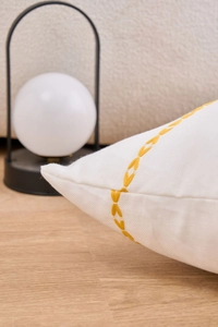 Detail shot of beige cotton linen cushion cover with yellow geometric V-shaped embroidery