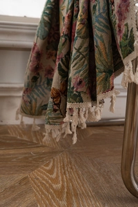 Detail of vintage floral jacquard woven throw blanket with decorative fringe edges