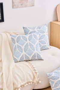 Detailed view of two blue and white geometric leaf pattern cushion covers on a sofa