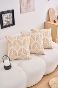 Detailed close-up of three square pillows with golden geometric leaf patterns on beige fabric