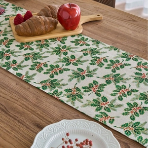 Christmas table runner with green holly leaves and red berries on a rustic wooden table
