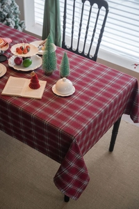 Close-up of thick red plaid Christmas tablecloth with festive dinnerware and decor