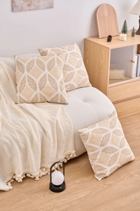 Detailed view of geometric pattern pillow covers in cream and gold on a cozy sofa