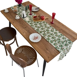 Christmas holly leaves and red berries table runner on rustic wooden dining table