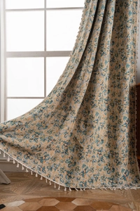 Detail of floral jacquard curtain fabric with blue and orange patterns and beige tassels