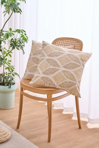 Close-up of two geometric throw pillow covers on a rattan chair in a cozy room