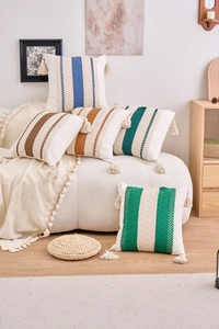 Detail of colorful striped pillow covers with handmade tassels on a plush sofa