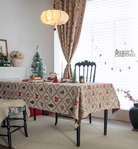 Close-up of jacquard Christmas tablecloth with red bows, green trees and floral motifs