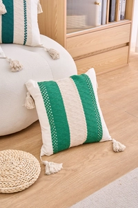 Detail of bohemian cream pillow cover with green crochet stripes and tassels