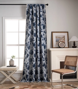 Close-up of blue floral curtain fabric featuring vintage patterns and cream tassel trim