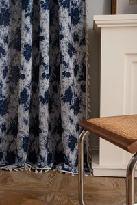 Close-up of geometric floral curtains with cream fringe tassels on the side edge