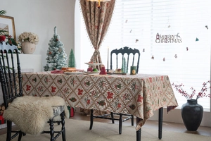 Detail of Christmas tablecloth featuring red bows, green trees, and reindeer pattern